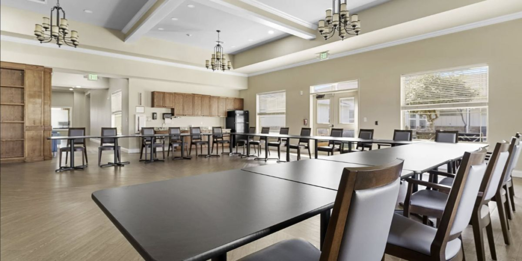 A spacious room featuring durable metal tables and chairs, suitable for high-traffic areas like dining halls and common spaces.
