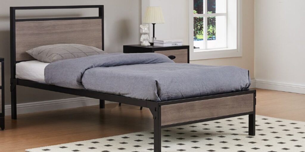 A metal-framed bed with a wooden headboard, designed for space efficiency in shared accommodations.