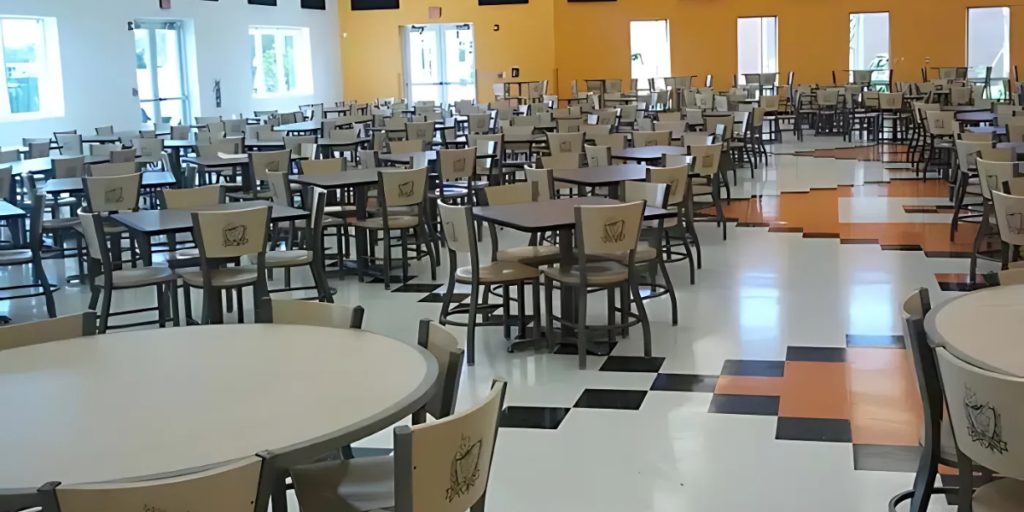 A spacious cafeteria featuring numerous tables and chairs arranged for group dining and social interaction.