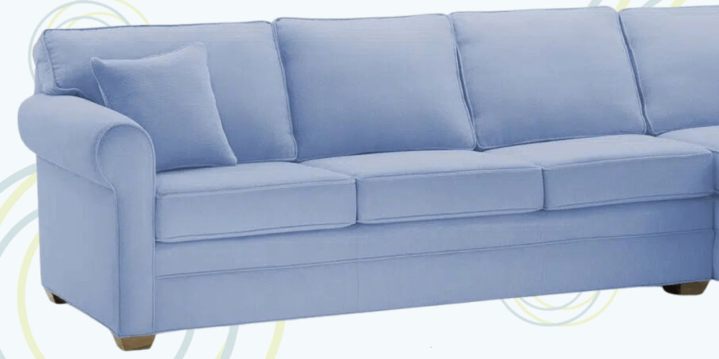 A blue sectional couch with a round ottoman, designed for comfort and functionality in high-traffic environments.