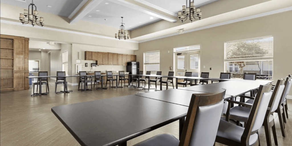 A spacious room furnished with multiple tables and chairs, suitable for gatherings or meetings.