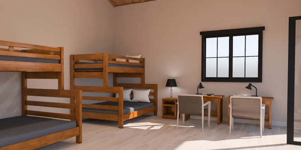 A room featuring bunk beds and a desk, designed for efficient use in a homeless shelter environment.