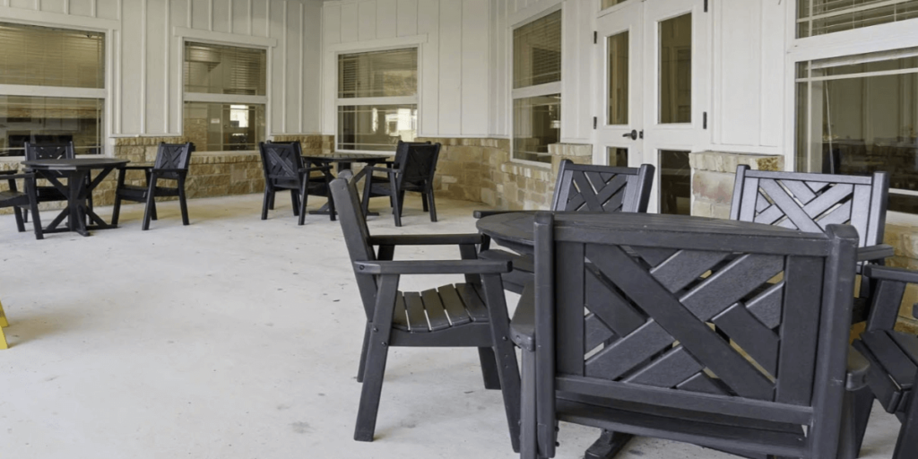 A patio featuring black chairs and tables, providing a stylish outdoor seating area for relaxation and gatherings.