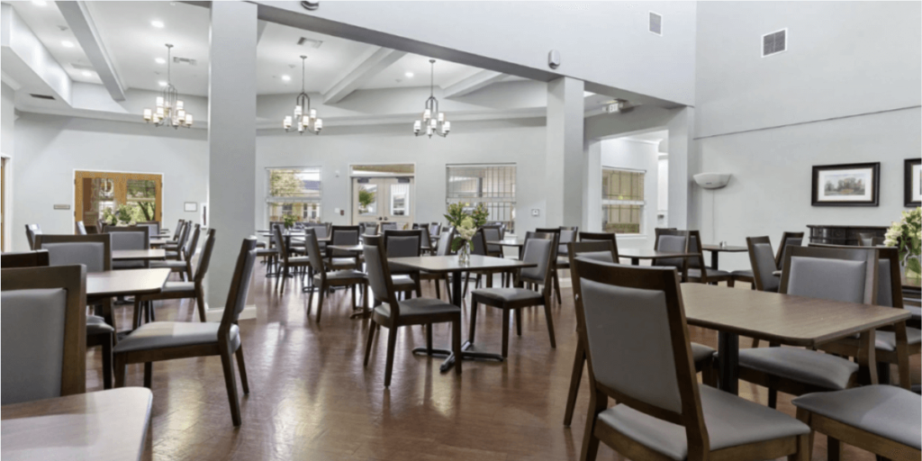 Dining room in a senior living community, featuring tables and chairs arranged for communal dining and social interaction.