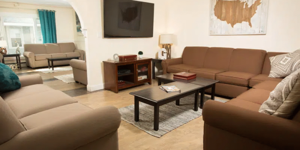 A cozy living room featuring comfortable couches and a television, designed for group living and healing environments.