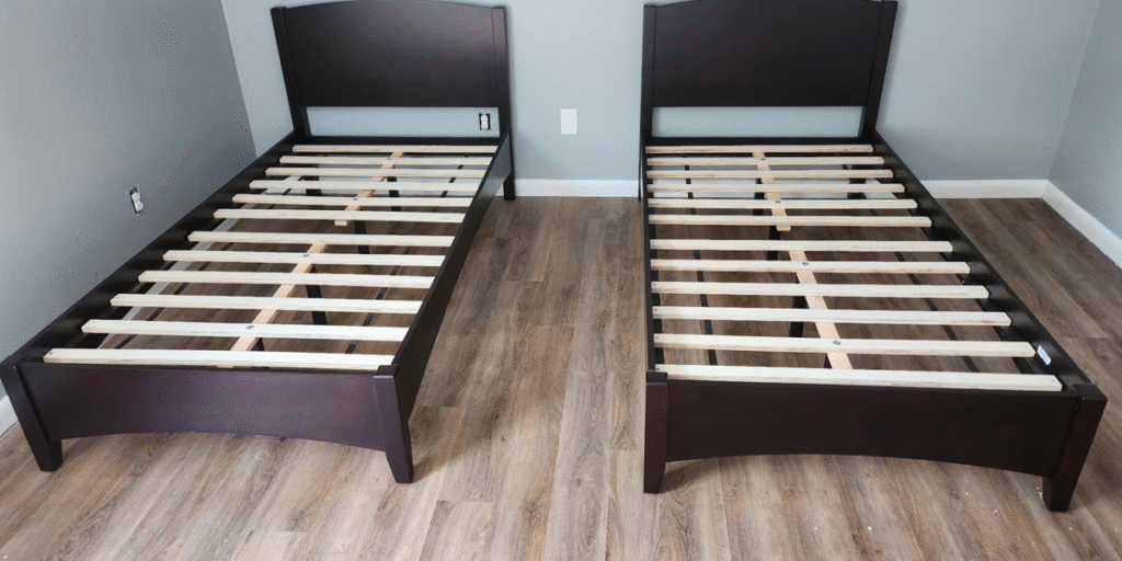 Two twin beds with wooden slats, highlighting the maintenance challenges of wooden frames compared to metal ones.